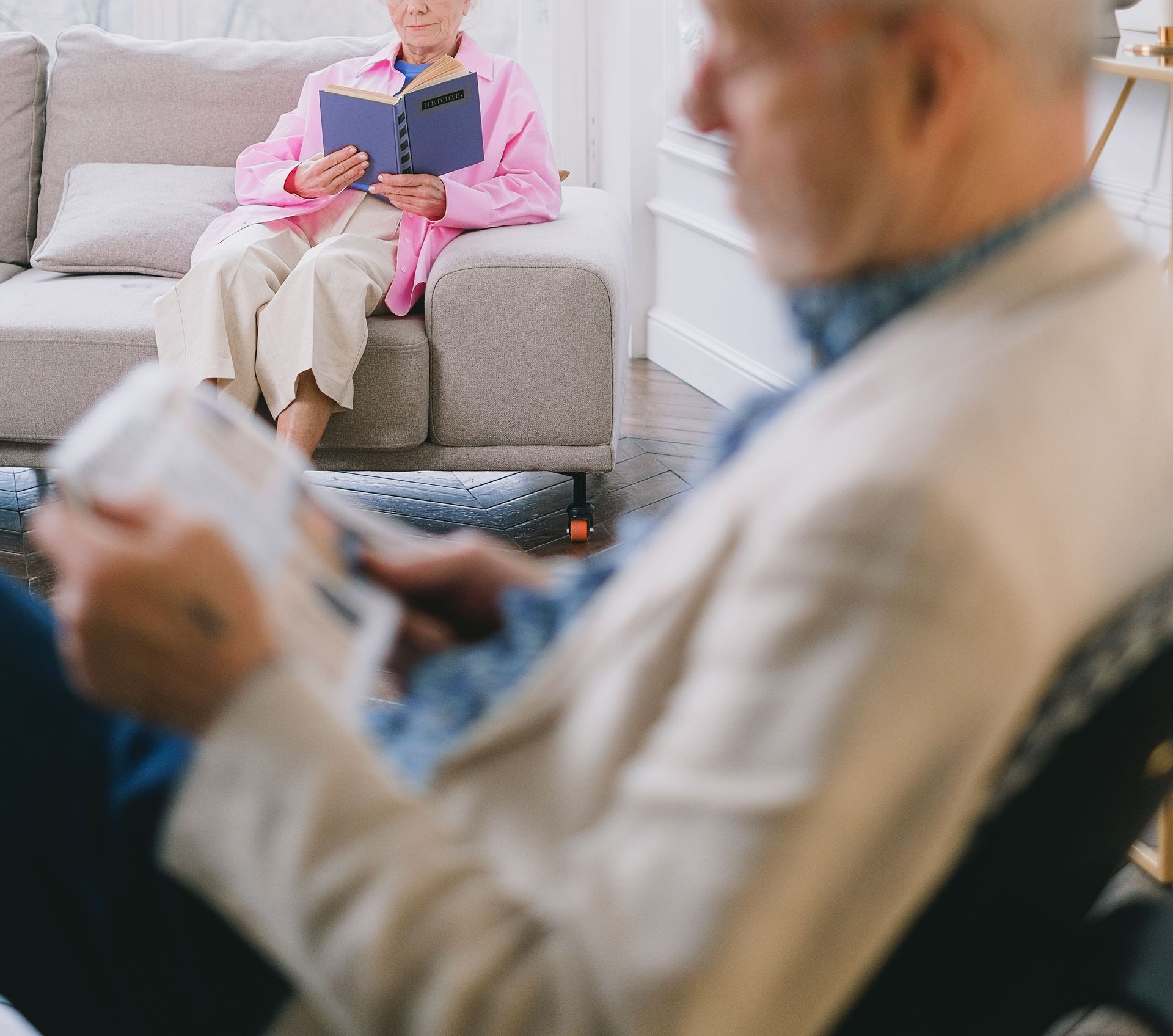A senior couple enjoys reading in a cozy, well-lit living room with modern decor.