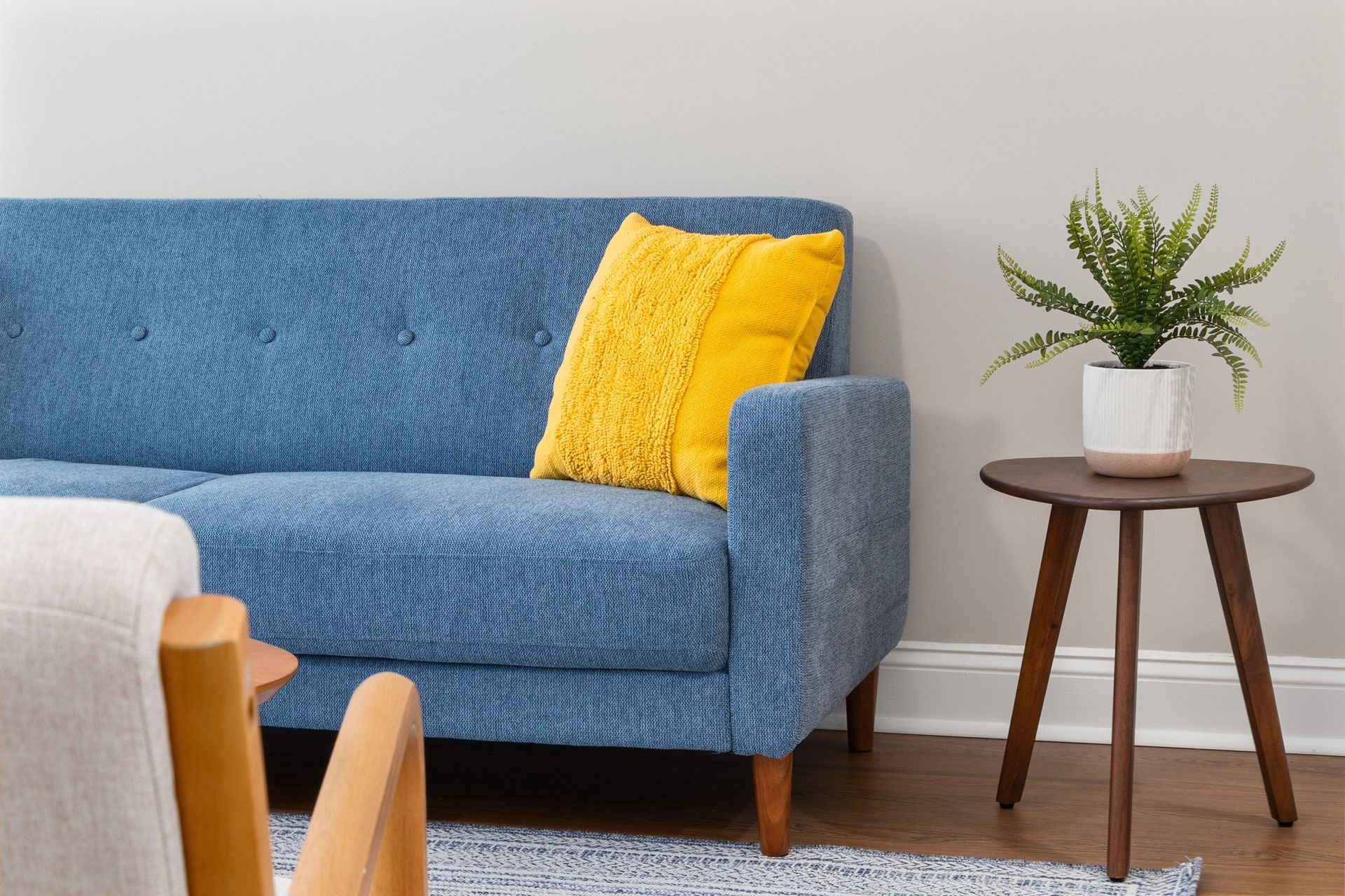 Contemporary living room featuring a stylish blue sofa with a bright yellow pillow and a wooden side table.