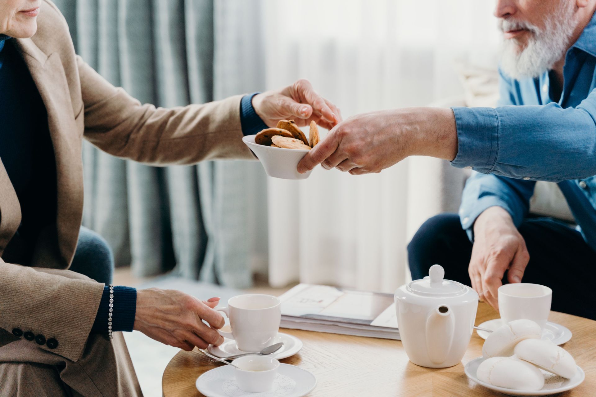 Two adults sharing cookies during a cozy coffee break indoors, enjoying companionship.